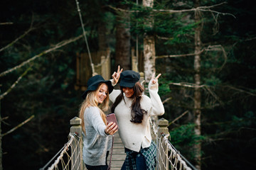 Two woman enjoying her friendship at bridge between trees.
