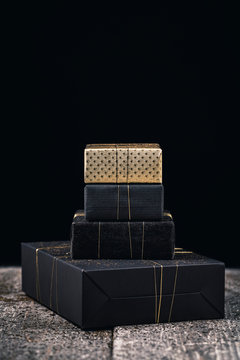 Gifts wrapped in black and gold on wooden surface