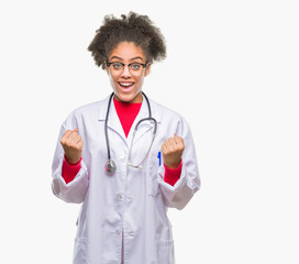 Young afro american doctor woman over isolated background celebrating surprised and amazed for success with arms raised and open eyes. Winner concept.