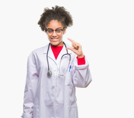 Young afro american doctor woman over isolated background smiling and confident gesturing with hand doing size sign with fingers while looking and the camera. Measure concept.