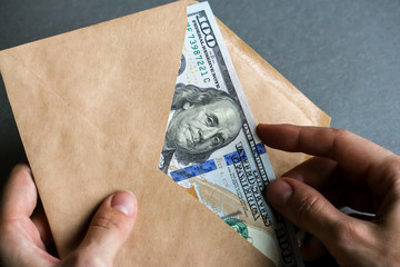 Hands holding envelope with dollar banknotes.