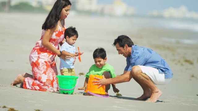 A Hispanic family having fun play and making sandcastles on summer vacation by the coast 