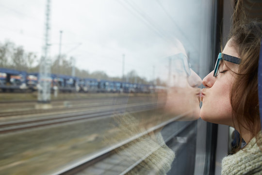 Young woman kissing herself at the reflection of a train window