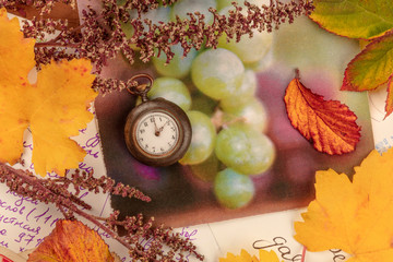 Nostalgia. A vintage watch with autumn leaves and old postcards, shot from above