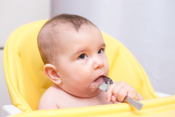 mother feeding her baby son with fruit puree