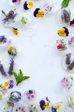 Flowers and frozen fruit on white marble background 