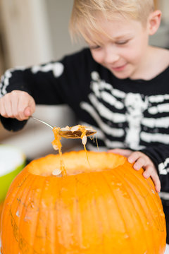 Boy scoops out pumpkin seeds while making a Halloween jack-o-lan