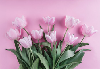 Bouquet of pink tulips flowers over light pink background. Greeting card or wedding invitation. Flat lay, top view, copy space