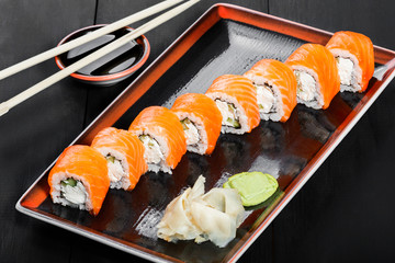Sushi Roll - Maki Sushi made of salmon, cucumber, avocado and cream cheese on dark wooden background. Top view. Japanese cuisine