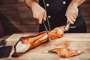Chef Hands cutting grilled rabbit for steaks with knife on cutting board. Hot Meat dishes