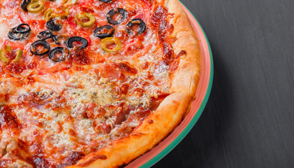 Mixed pizza Italian food with chicken, tomatoes, mushrooms, ham, salami, olive and cheese on dark wooden background. Homemade pizza.