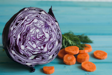A photo of the purple cut cabbage and pieces of carrot and dill on a bright blue background.