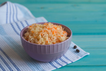 Photo of cabbage and carrot salad in a plate on a bright blue background.