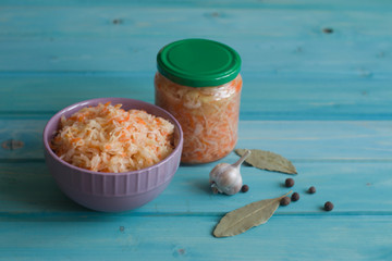Photo of sauerkraut in a jar and plate on a bright blue background.