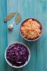 Photo of sauerkraut and salad of purple cabbage on a bright blue background.