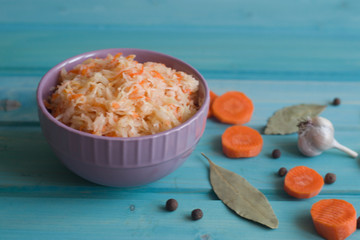 Photo of sauerkraut plate and carrots and garlic on a bright blue background.