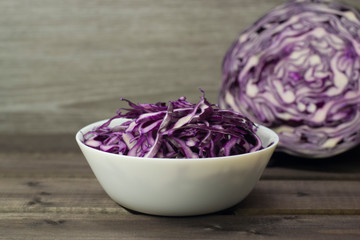 Photo of the salad of purple cabbage in plate close-up on a wooden background.