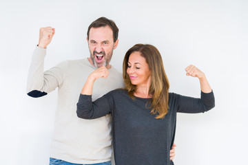 Beautiful middle age couple in love over isolated background showing arms muscles smiling proud. Fitness concept.