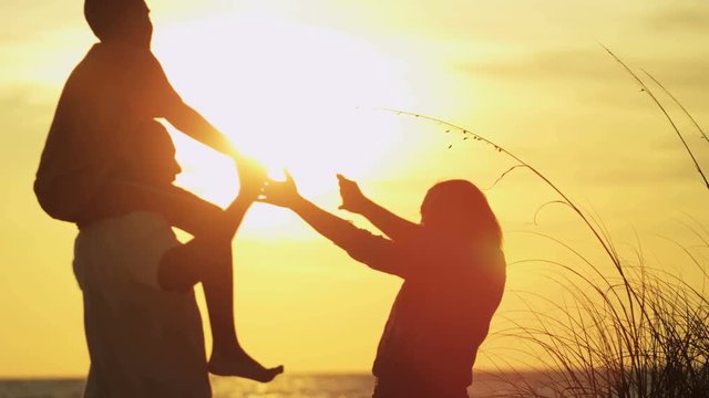 Silhouette of carefree ethnic family enjoying sunset and having fun on the beach RED EPIC