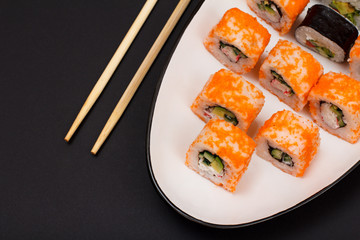 Uramaki California. Sushi rolls on a plate with wooden sticks.