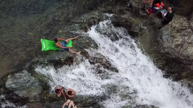 Bird eye view of a man relaxed on the edge of El Ataud Waterfall on an inflatable.