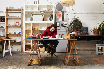 Full Length Of Artist Painting At Desk In Studio