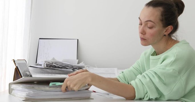 Woman bored doing paper work at home with Folders Working At Desk