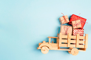 Wooden toy truck  with Christmas gift boxes on blue background and copy space.