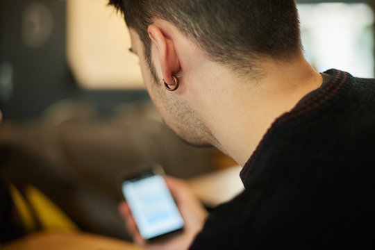 Young man  with earring ooking at the screen of the phone