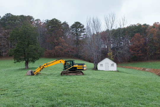 Track excavator and building in grassy field