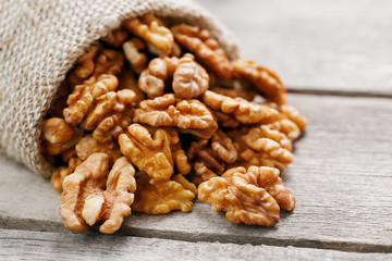 Walnuts in a burlap bag on a wooden gray background.