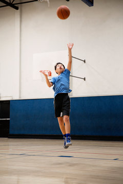 Young asian basketball player jumping high for a layup