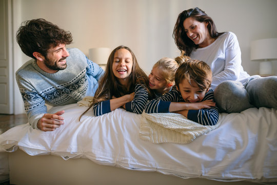 Portrait of happy family wearing pajama resting on bed. 