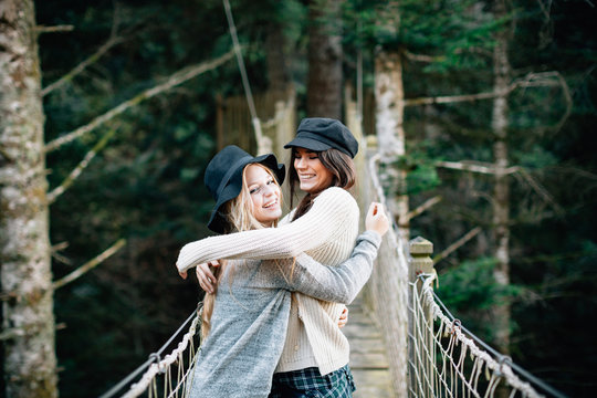 Two woman enjoying her friendship at bridge between trees.