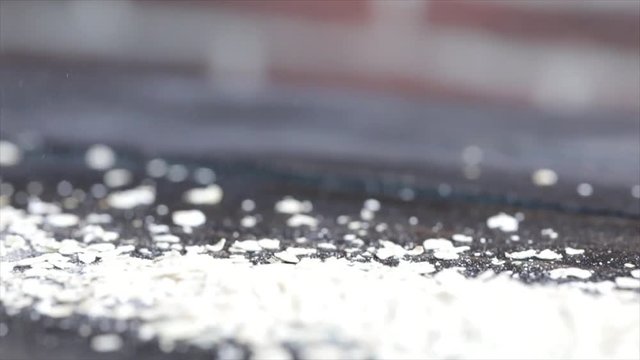 Oat Flakes are Falling onto a Dark Wooden Table, Closeup