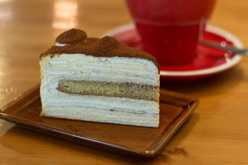 mille crepe cake on a small plate with coffee in a carafe