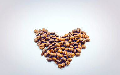 The heart is made of coffee beans on a white background, the side edges are made of dark margins. Leave space for adding text.
