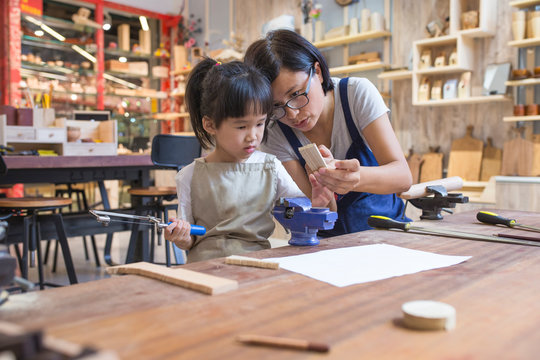 Asian womant with her kid doing carpenter job in the studio