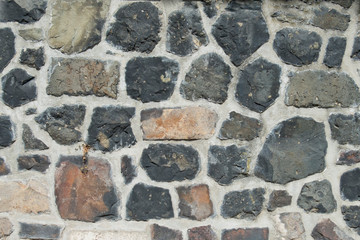 polygone Mauer aus Naturstein  von grau bis rostfarbig mit Fugen aus Mörtel