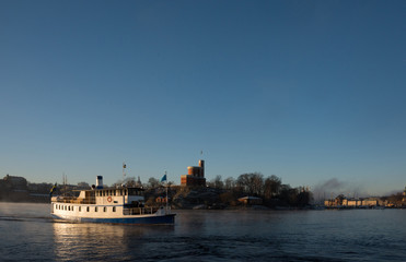 Fototapeta na wymiar A sunny morning in stockholm harbour, ships and boats in the frosty mist and winter light