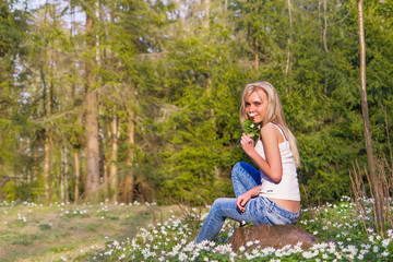 Pretty blonde woman on a spring meadow in blossom flowers