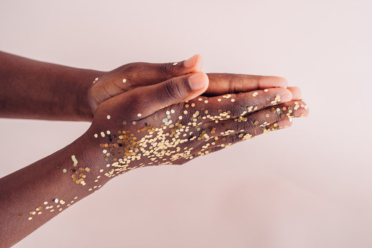 Black girl's hands with golden confetti