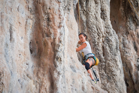 Young woman rock climbing on karst limestone white mountain in Thailand