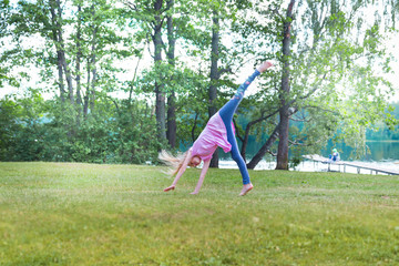 Little blonde girl turning cartwhell outdoors on grass