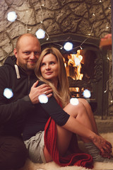 Fototapeta na wymiar Pretty couple near fireplace ready for winter frosts