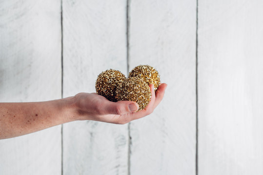 Hand holding sparkly golden Christmas tree decorations