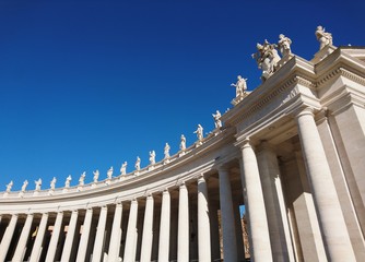 St. Peter's Basilica in Roma with columns and fountains on a sunny day with blue sky