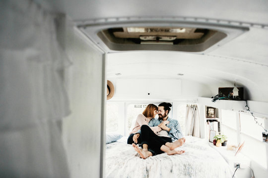 Cute hipster couple cuddling in converted school bus tiny home