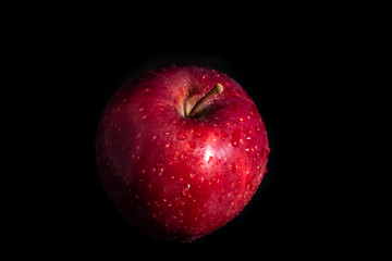 Red apple in water drops on a black background