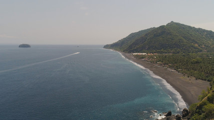 beach with black volcanic sand, mountains in tropical resort. aerial seascape sand beach with turquoise water. Seascape, ocean and beautiful beach.Travel concept. Indonesia, Bali